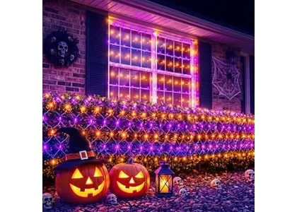 The image shows a spooky Halloween scene with glowing orange lights illuminating trees and bushes.