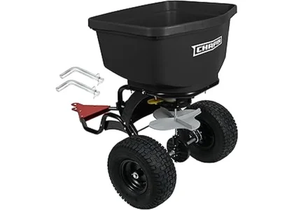 This image shows a person using a large wheeled seed spreader on a vast green lawn.