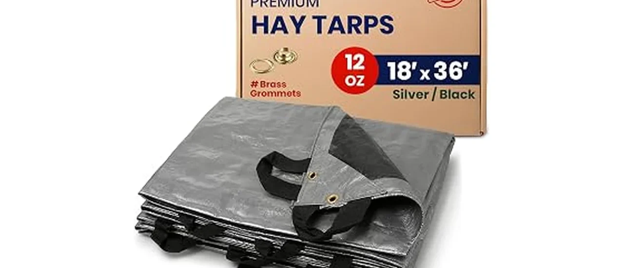 The image shows a stacked pile of hay covered securely with a heavy-duty tarp for protection.