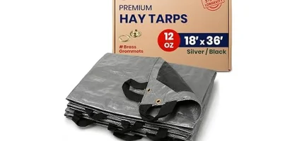 The image shows a stacked pile of hay covered securely with a heavy-duty tarp for protection.